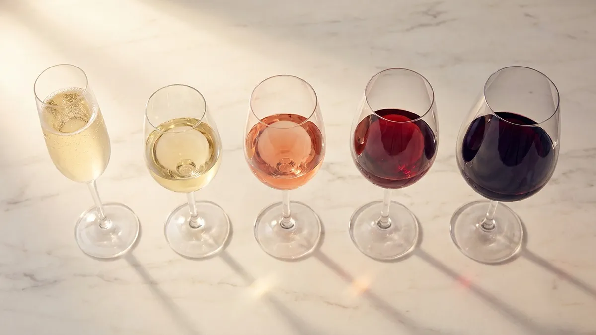 A standard 5oz pour of red wine on a kitchen counter next to a measuring jigger