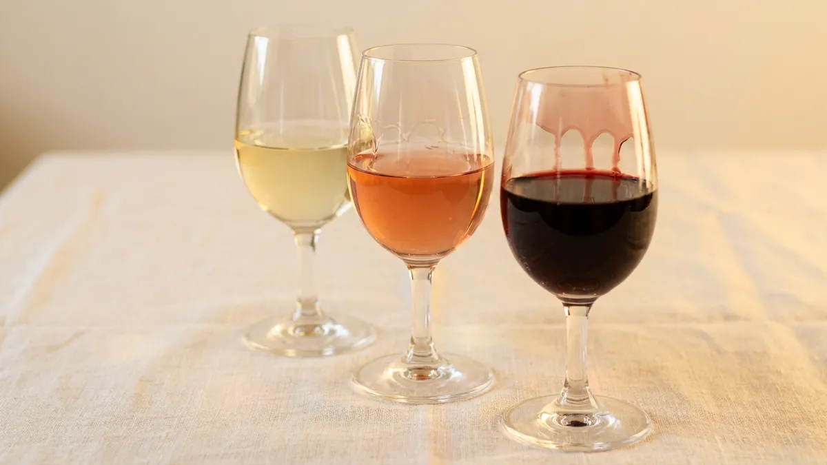 Three wine glasses showing light white, medium red, and deep full-bodied red wine