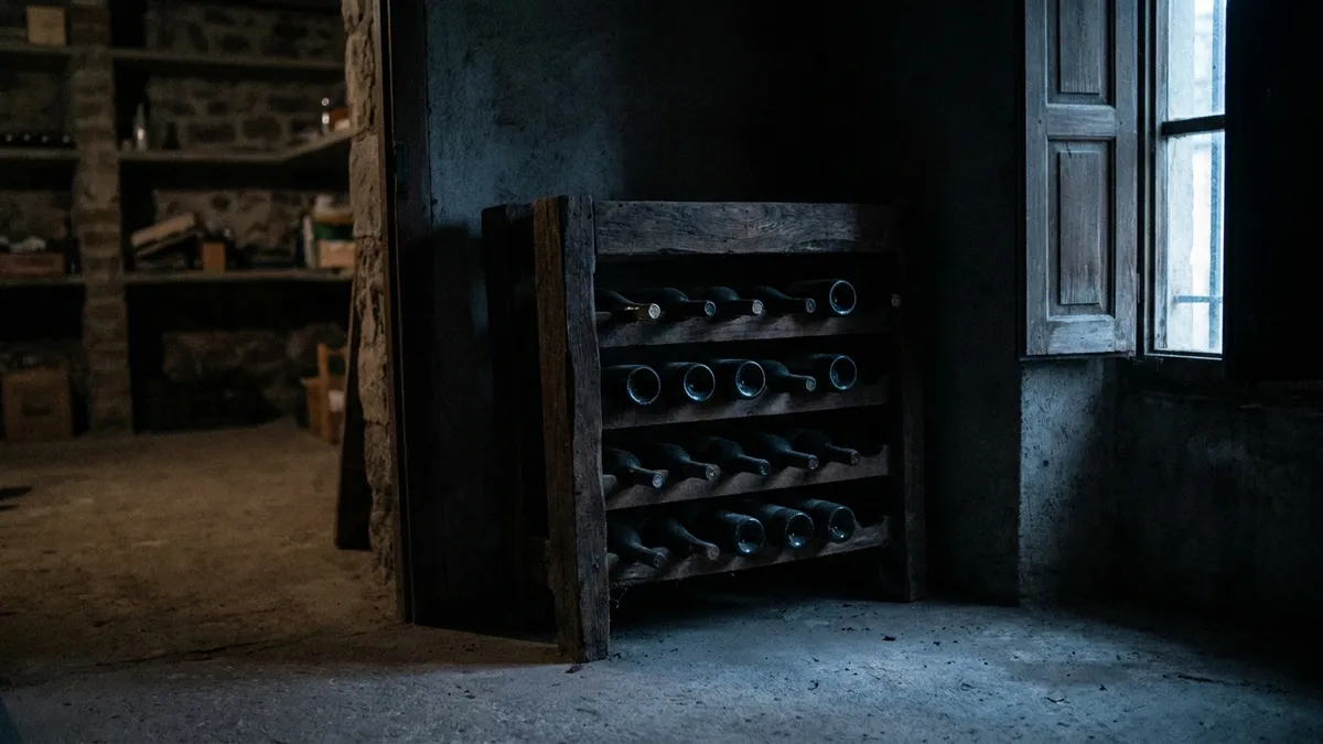 A dim, cool closet corner with a small wine rack tucked away from a window